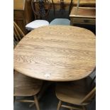 An Ercol light coloured Elm dining table with an e