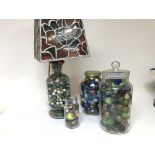 A bottle lamp base full of old marbles and three j