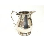 A solid silver cream jug with a scroll handle Birm