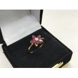 A 9ct gold ruby and diamond flower design ring.