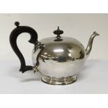 A silver tea pot of cylindrical shape with a hardw