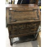 An oak bureau with a hinged full front above two d