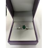 A 18 ct white gold ring with central emerald surro