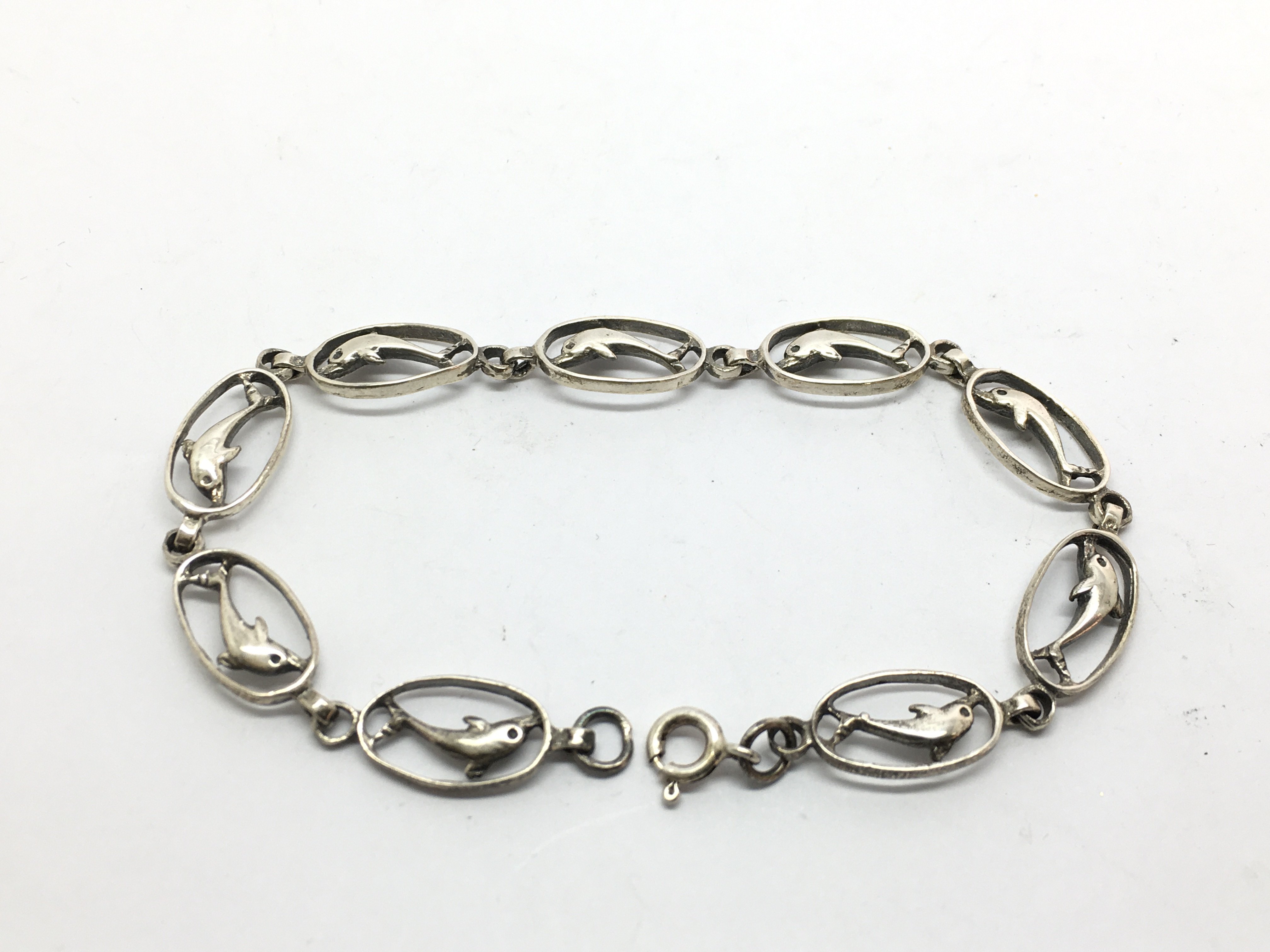 A silver bracelet, the links in the form of dolphi