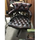 A brown leather button down office chair with turned supports. Swivel seat