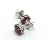 A pair of silver studs set with treated rubies.