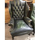 A Green leather wing arm chair with a button back and drop in seat of mid 18th century style.