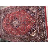 A Quality hand knotted wool carpet with a central blue medallion on a red floral field with a