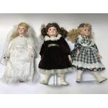 3 porcelain headed dolls, two are on a stand toget