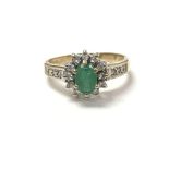 A 9 carat gold ring set with an emerald flanked by