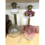 Two oil lamps, one having a pink glass shade and r