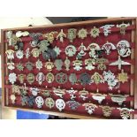 A large collection of military cap badges in four