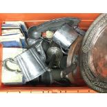 A box containing a collection of metal items including copper plates and pewter tankards together