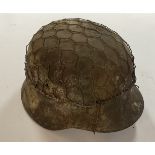 A WW1 German M16 infantry helmet with original camouflage paintwork, mesh wire and liner.