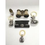 A vintage pair of binoculars, a silver rattle, two