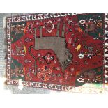 A hand knotted rug depicting a mythical beast to the centre on a red ground, approx 114cm x 157cm.