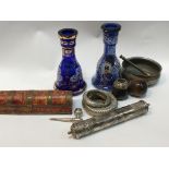 A collection of Middle Eastern items a white metal scroll case pipe bangles and two blue glass