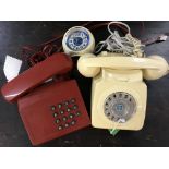 Two plastic dial telephones and a small desk clock