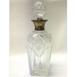 A cut glass decanter with a hallmarked silver neck