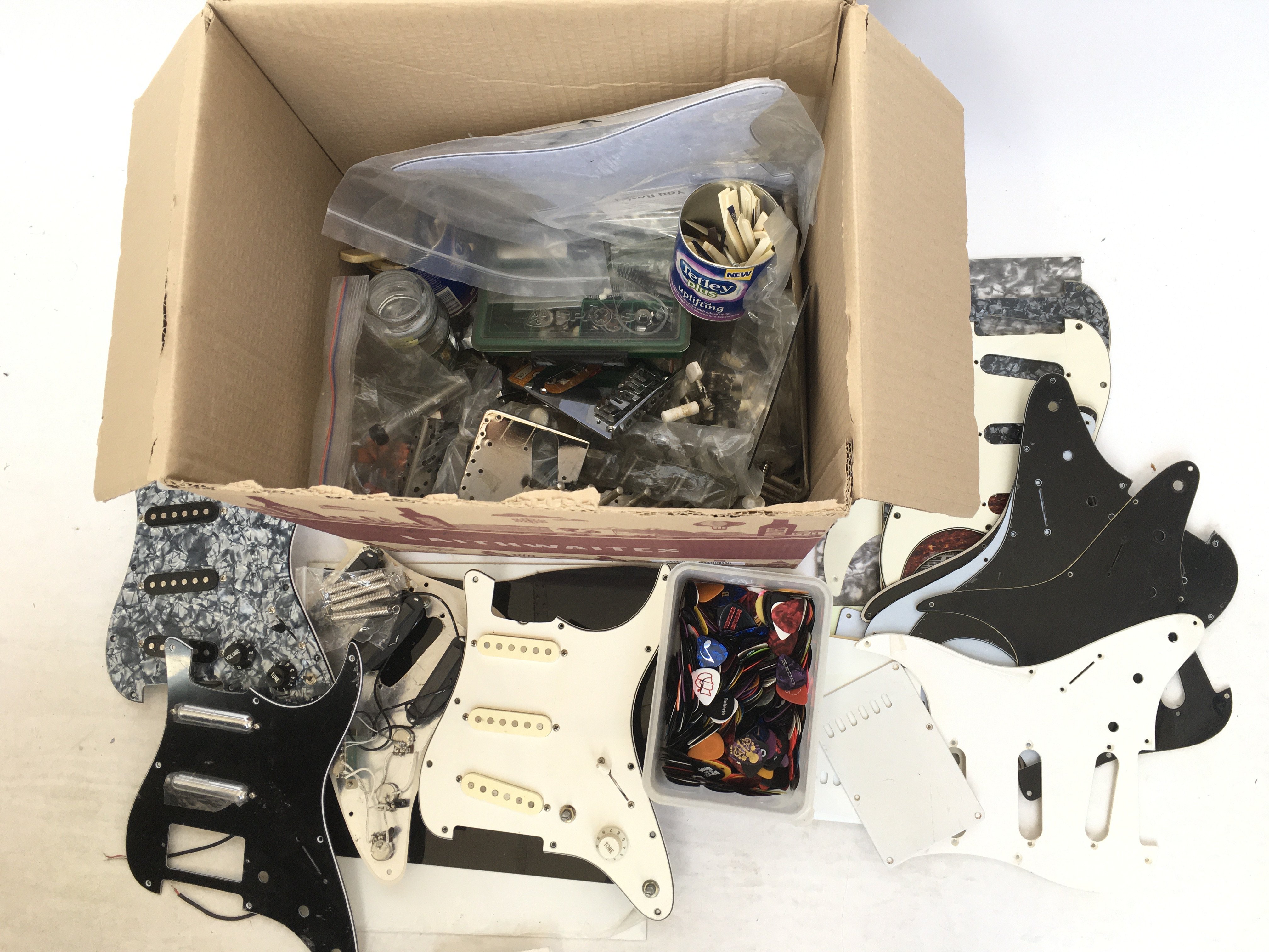 A box of guitar parts comprising three loaded Stra