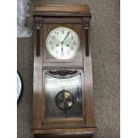 A vintage hanging walnut wall clock with swinging