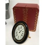 A Cartier traveling alarm clock on an Easel gilt metal stand oval dial manual wind seen working