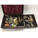 A red leather box containing various costume jewel