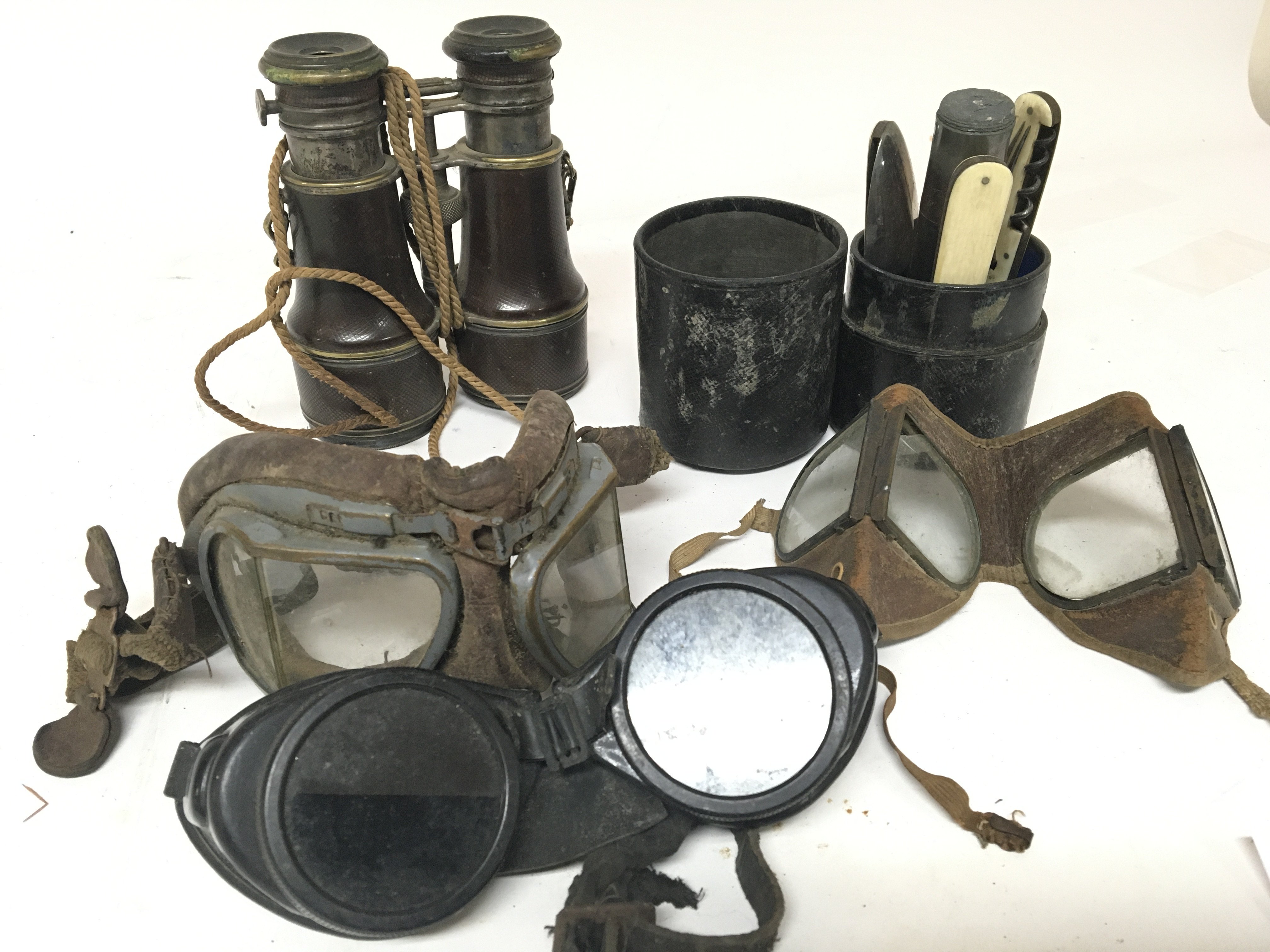 Three pairs of old flying goggles a pair of binoculars and a traveling cutlery set. (a lot)