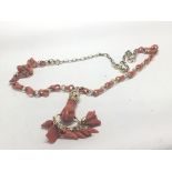 A gold and coral necklace with a hand pendent hold