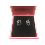 A pair of 9ct gold earrings set with cabochon amet