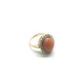 A gold ring set with a central coral surrounded by
