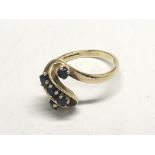 A 9ct gold ring set with a scrolling row of sapphi