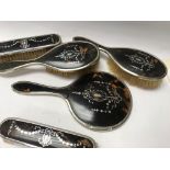 A five piece silver and tortoiseshell dressing table set comprising of a mirror and four hand