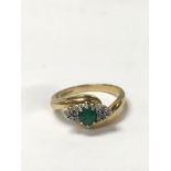 An 18ct gold emerald ring, set with small diamonds. The approximate ring size is P.