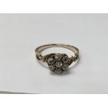 An unmarked gold ring set with diamonds in the shape of a flower. The approximate ring size is O.