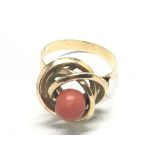 An unmarked gold ring set with a coral bead. Ring