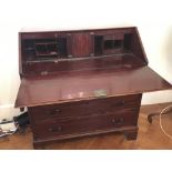 A George III mahogany bureau the fall front enclosing a well fitted interior above drawers. on