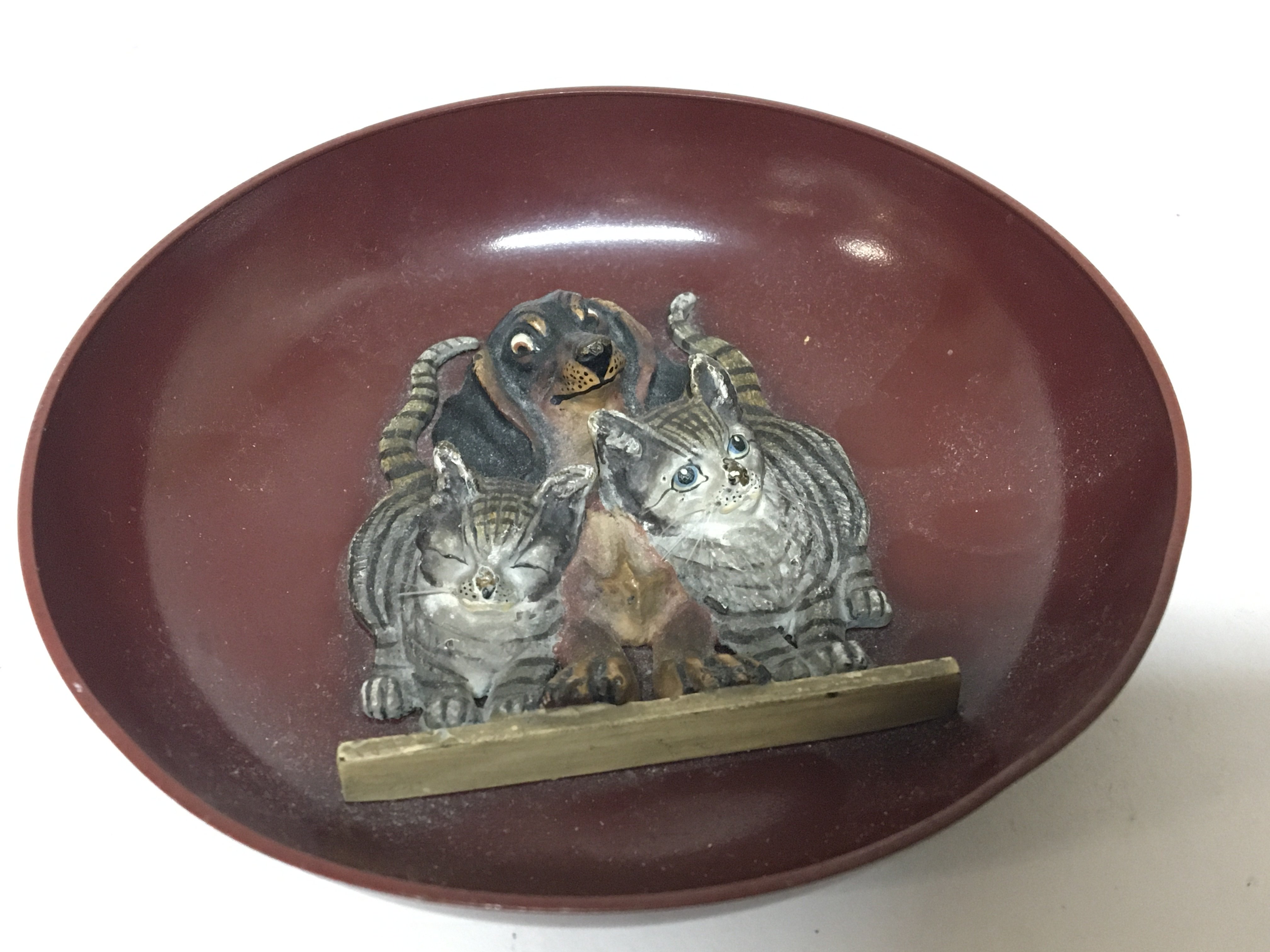 An unusual cold painted metal dish with raised cas