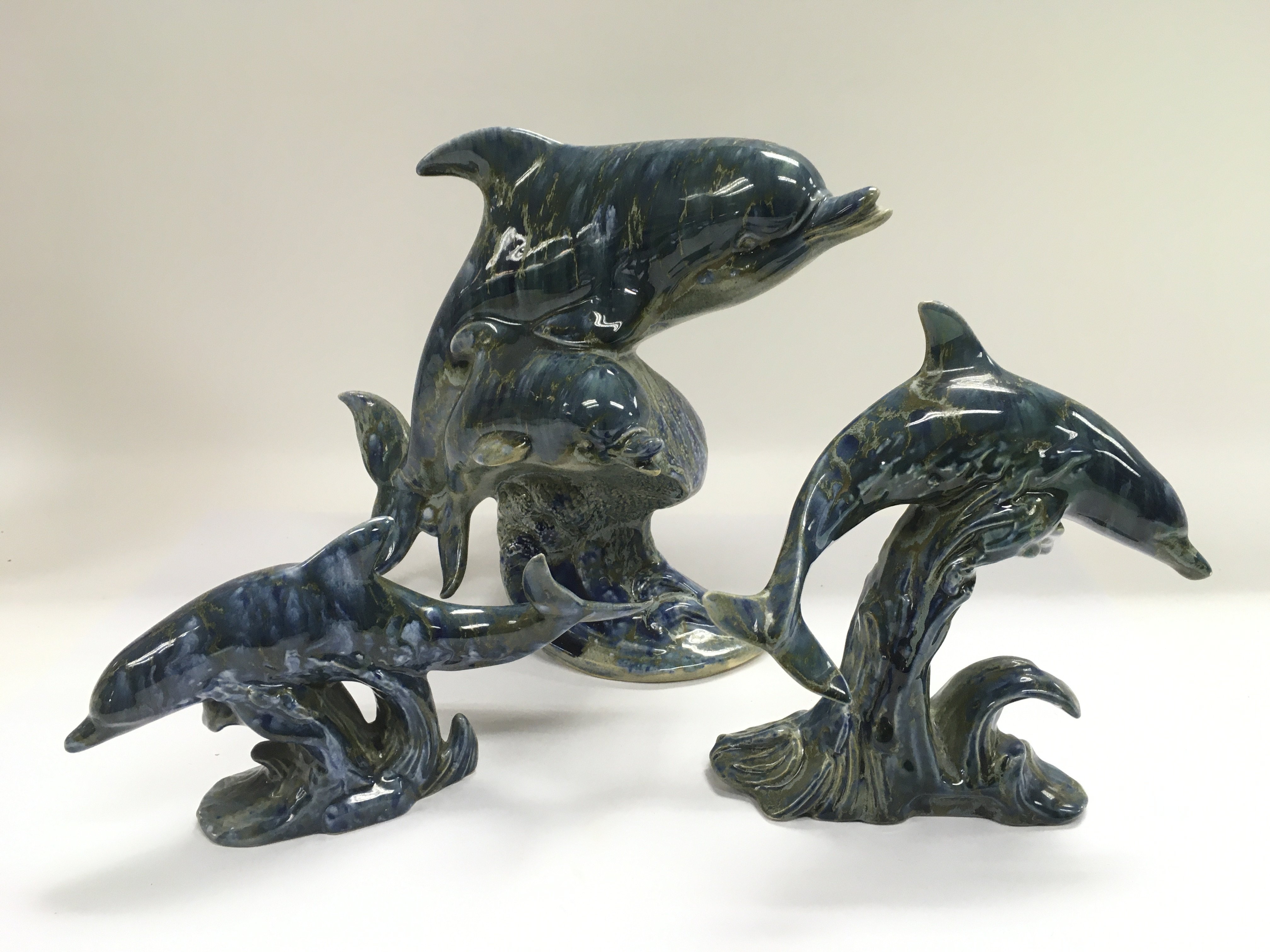 Three Sally Udall figures of dolphins.