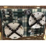 A wicker picnic basket with plates cups glasses an