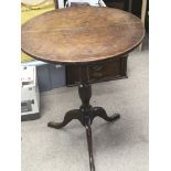 A late George III oak vernacular provincial wine table with a circular top on a turned column and