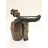 A carved black forest figural cigarette dispenser with a musical movement.