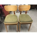 A pair of vintage chairs with green upholstered drop in seats on a wooden base by the designer