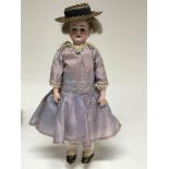 A bisque German doll on stand.