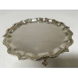 A silver card tray with a shaped edge and small fe