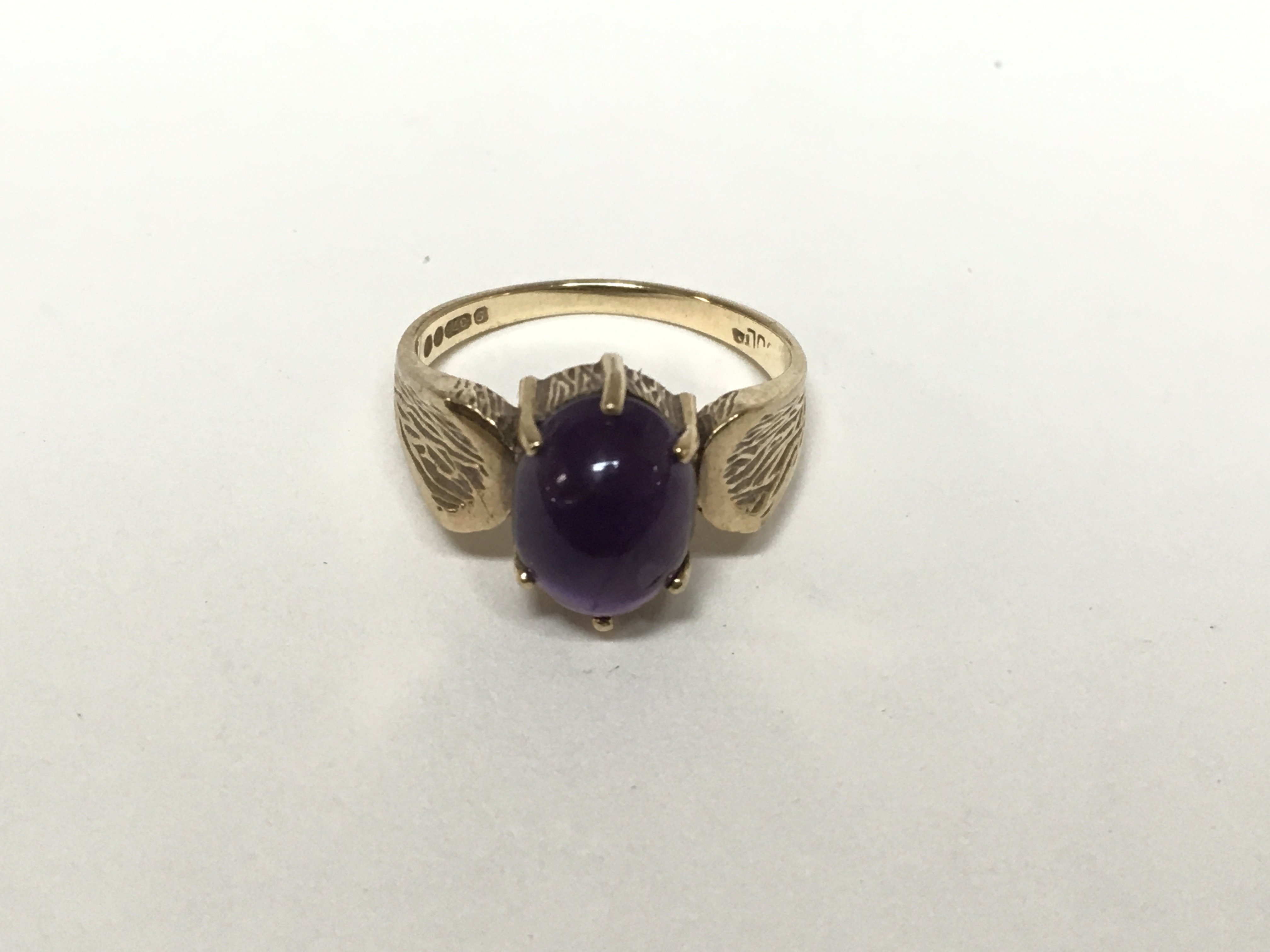 A 9ct gold ring set with an amethyst cabochon, the