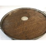 A silver plated and oak circular tray with twin ha