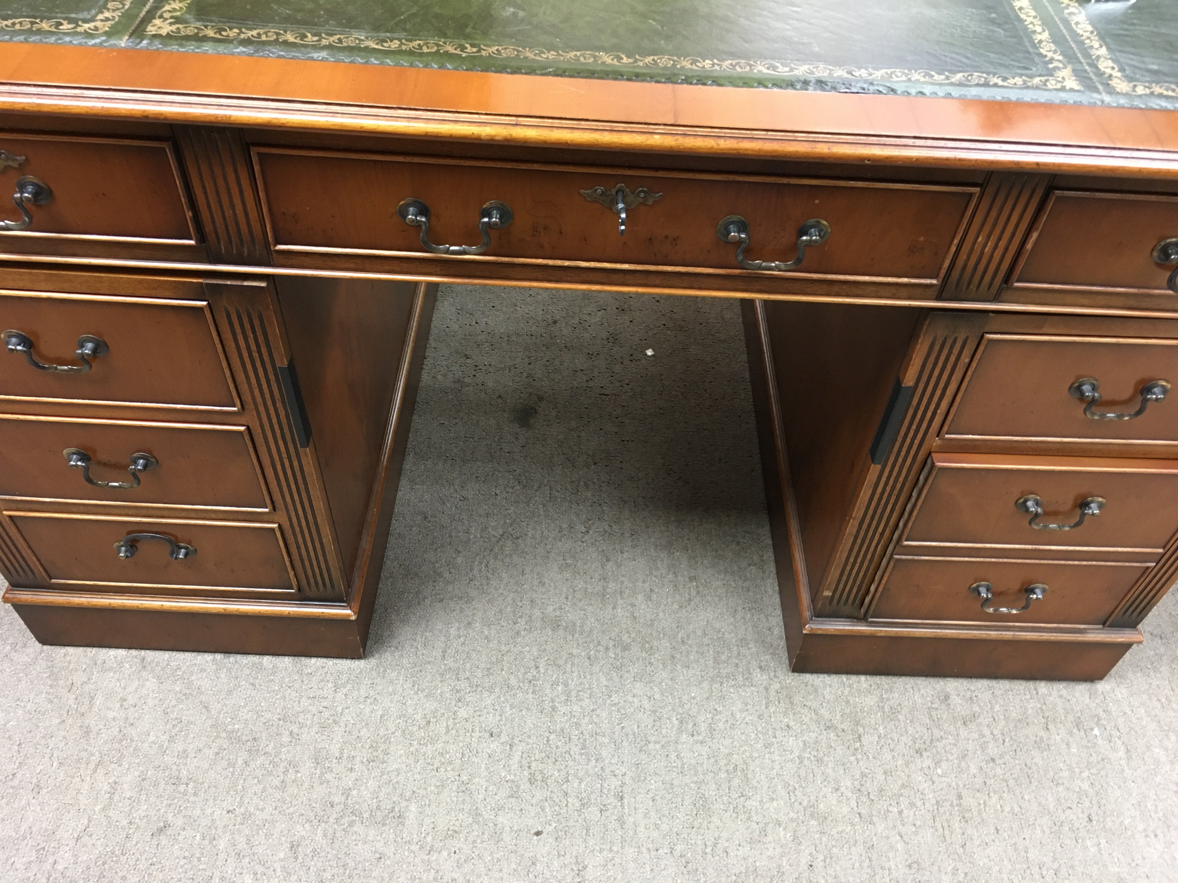 A reproduction pedestal desk fitted with 9 drawers