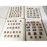 Four red stamp albums containing a good collection