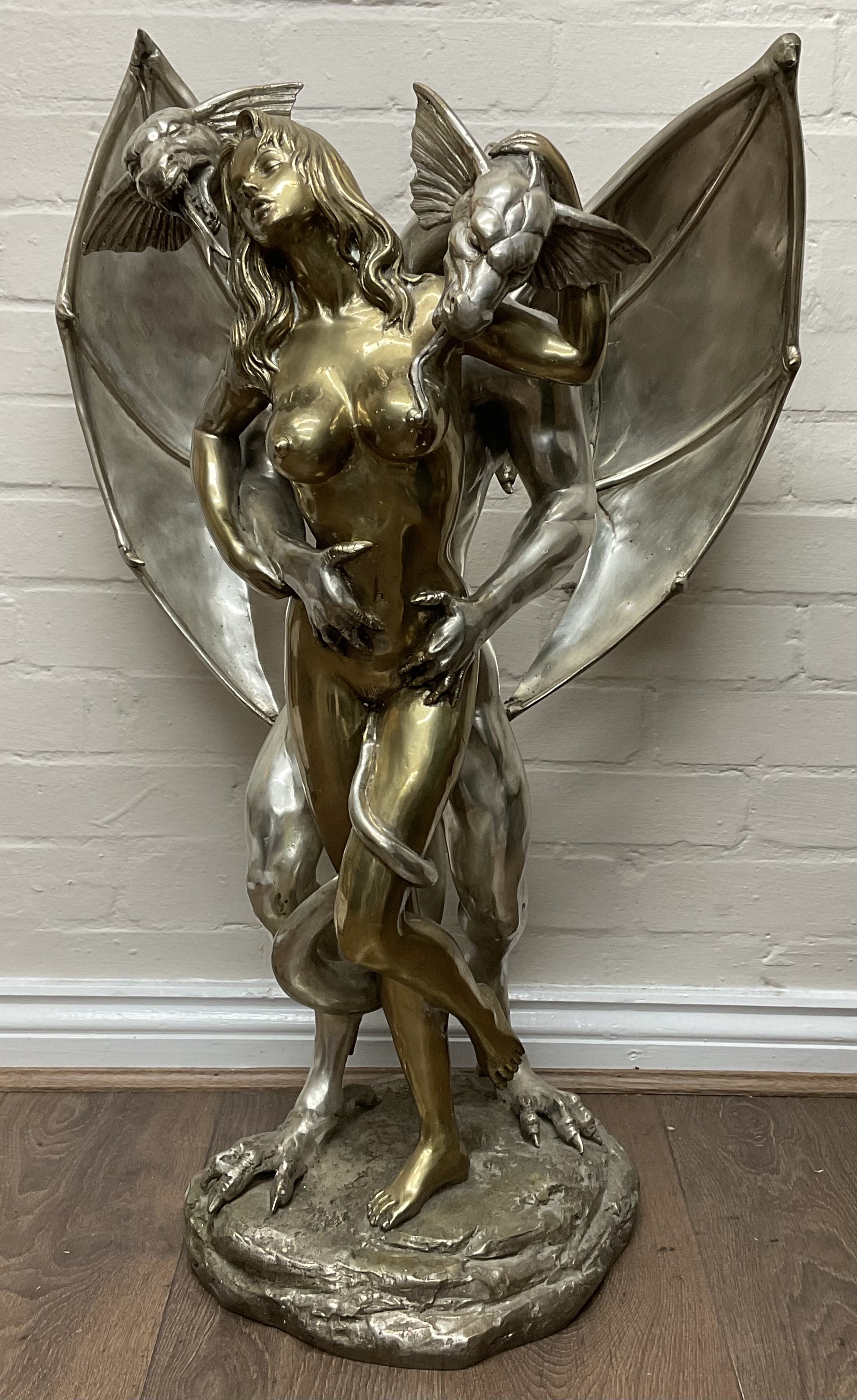 A large two tone polished bronze sculpture entitled Erotic Dragon of a double headed dragon and a nu